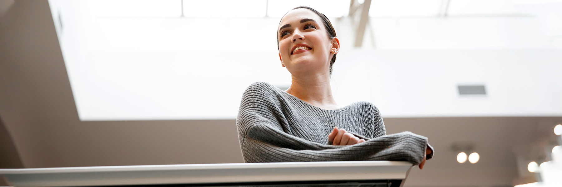 A student smiles and looks ahead while she leans on a counter in the central commons.