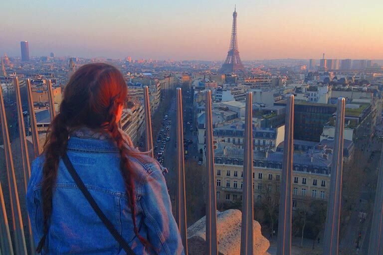 A student stands looking at the Eiffel Tower in Paris, France.