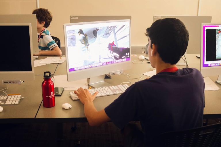 A student sits in a Media School lab working on a computer during Game Camp.