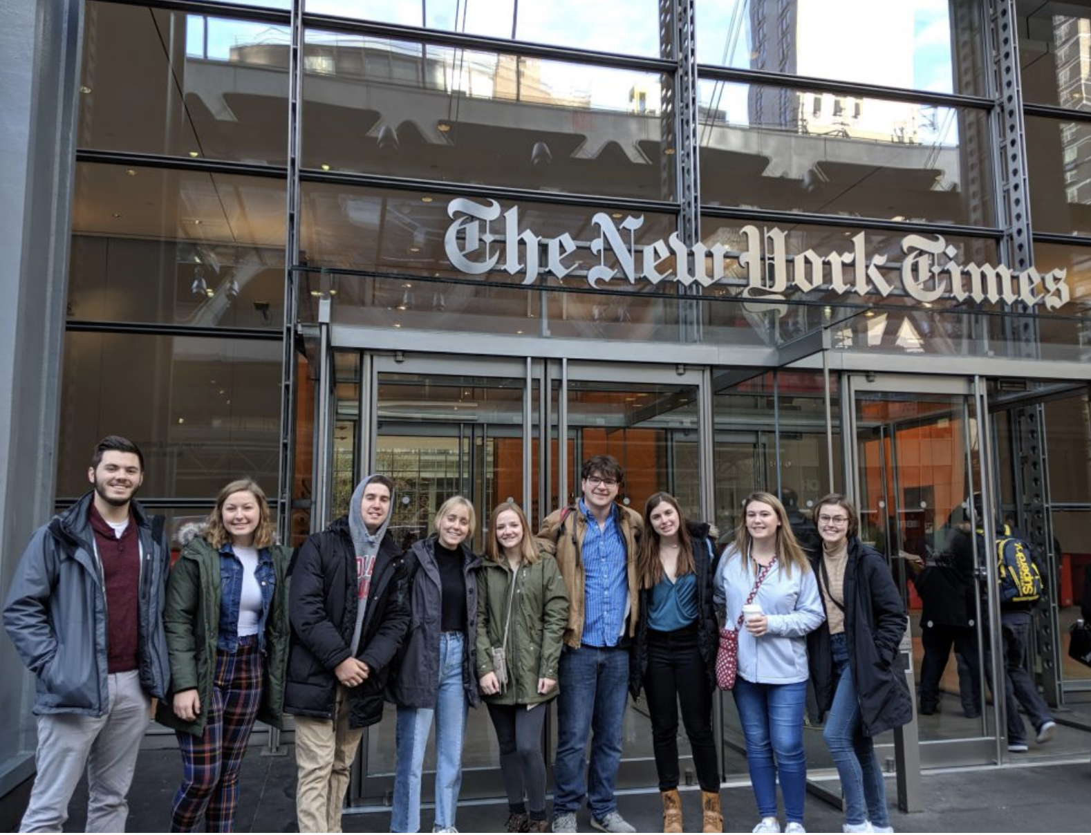 A group of students smile outside The New York Times building in New York City.