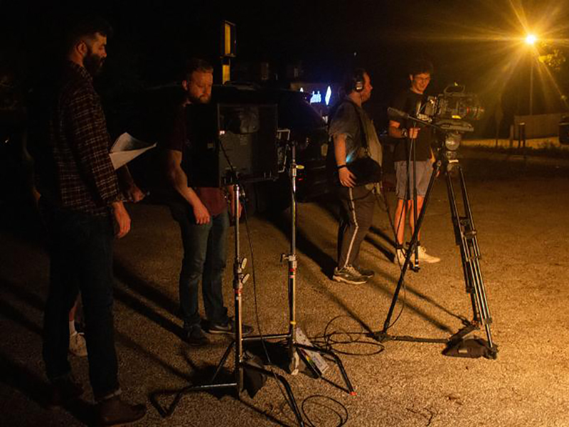 Students film a short video called "Rover." They are standing outside at night.