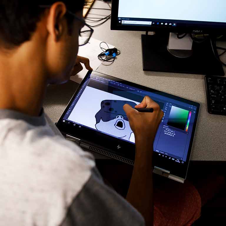 A student uses a writing tablet to make a design.