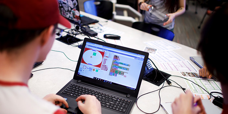Two students work on creating a video game on their laptop.