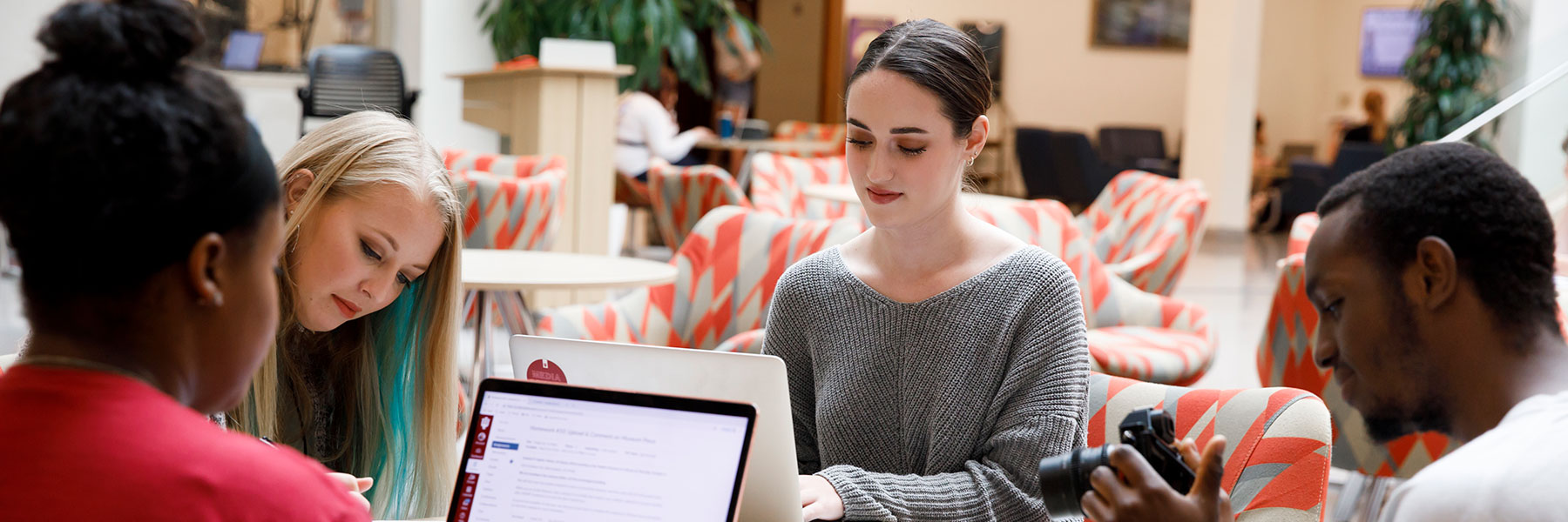 Four students sit at a table in the Franklin Hall commons doing homework.